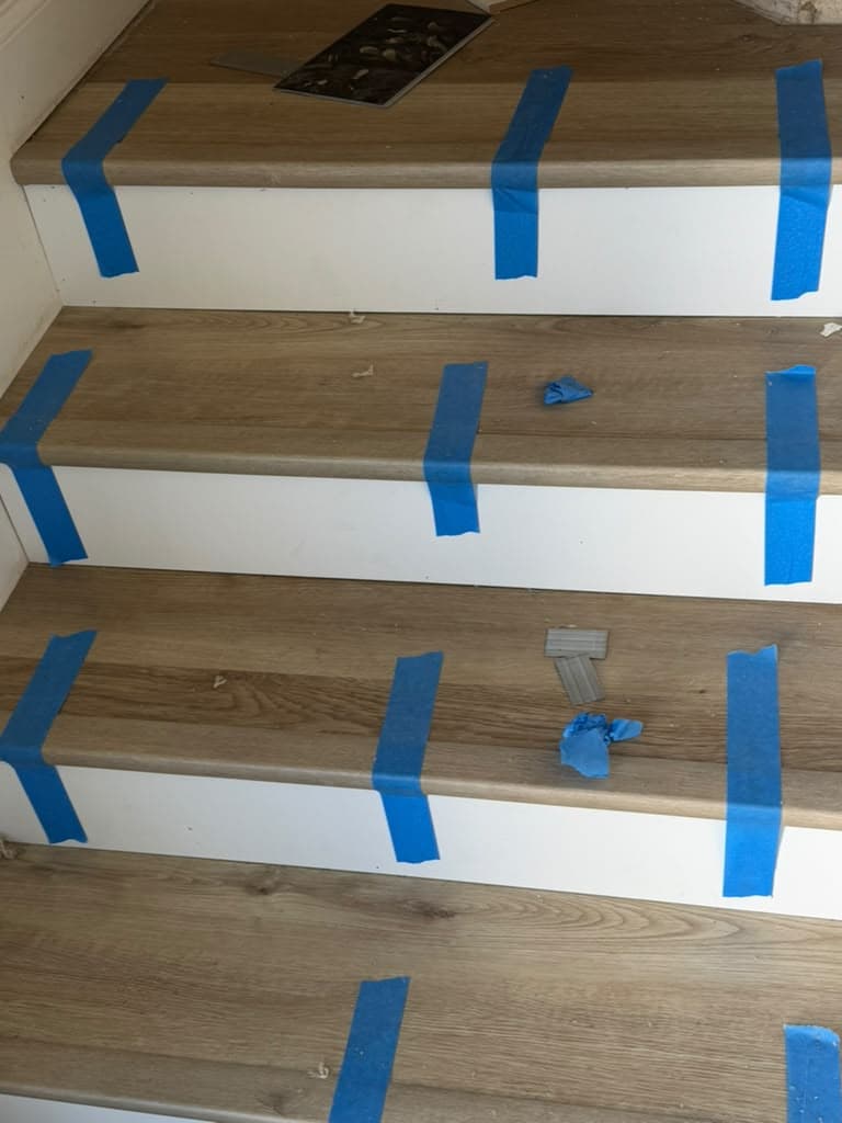 New stair treads being installed and taped while adhesive cures